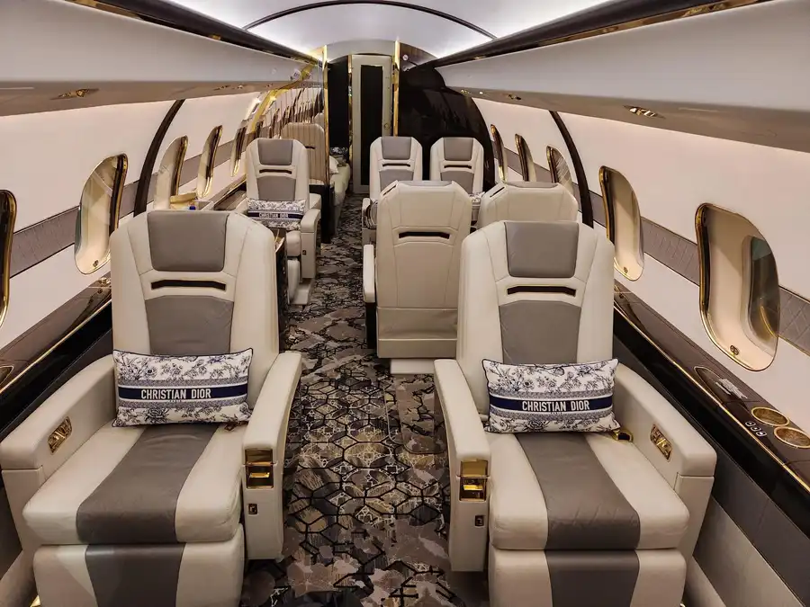 Cream leather club seat beside an oval window in a Bombardier Global cabin.