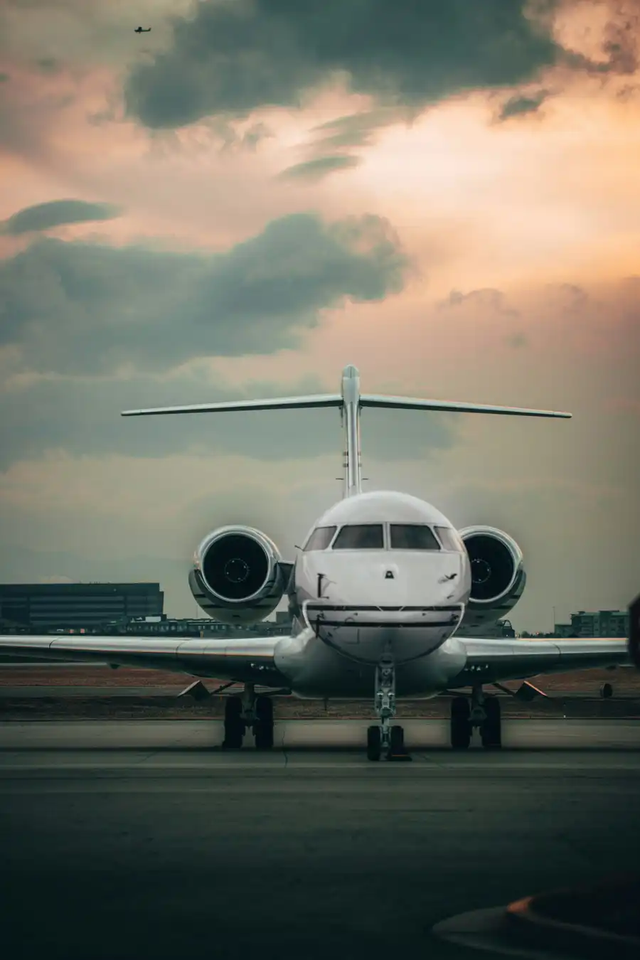 A Bombardier Global seen nose-on, parked on the ramp under a dusk sky.