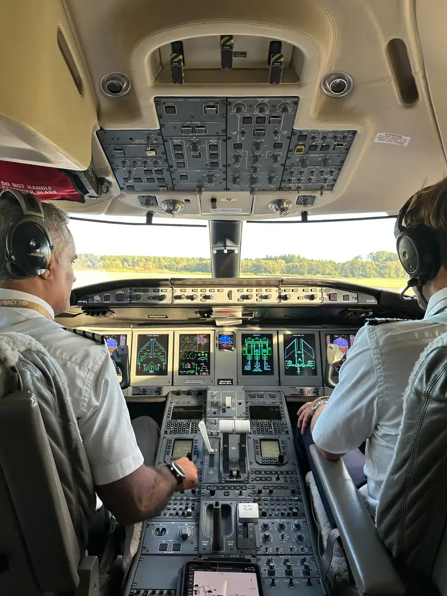 Two pilots at the controls of a Bombardier Global, seen from the jump seat.